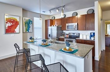 A kitchen with a white counter top and a black chair.